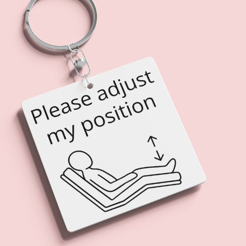 Keychain with 'Please adjust my position' text and icon on a pink background