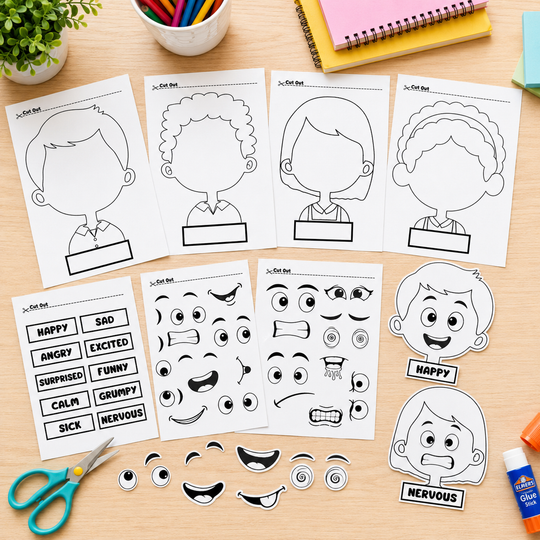 A set of printable face and expression activity sheets laid out on a wooden desk, with cut-out facial features, emotion words, and cartoon character head templates. Scissors, a plant, pens, and notebooks are visible around the sheets.