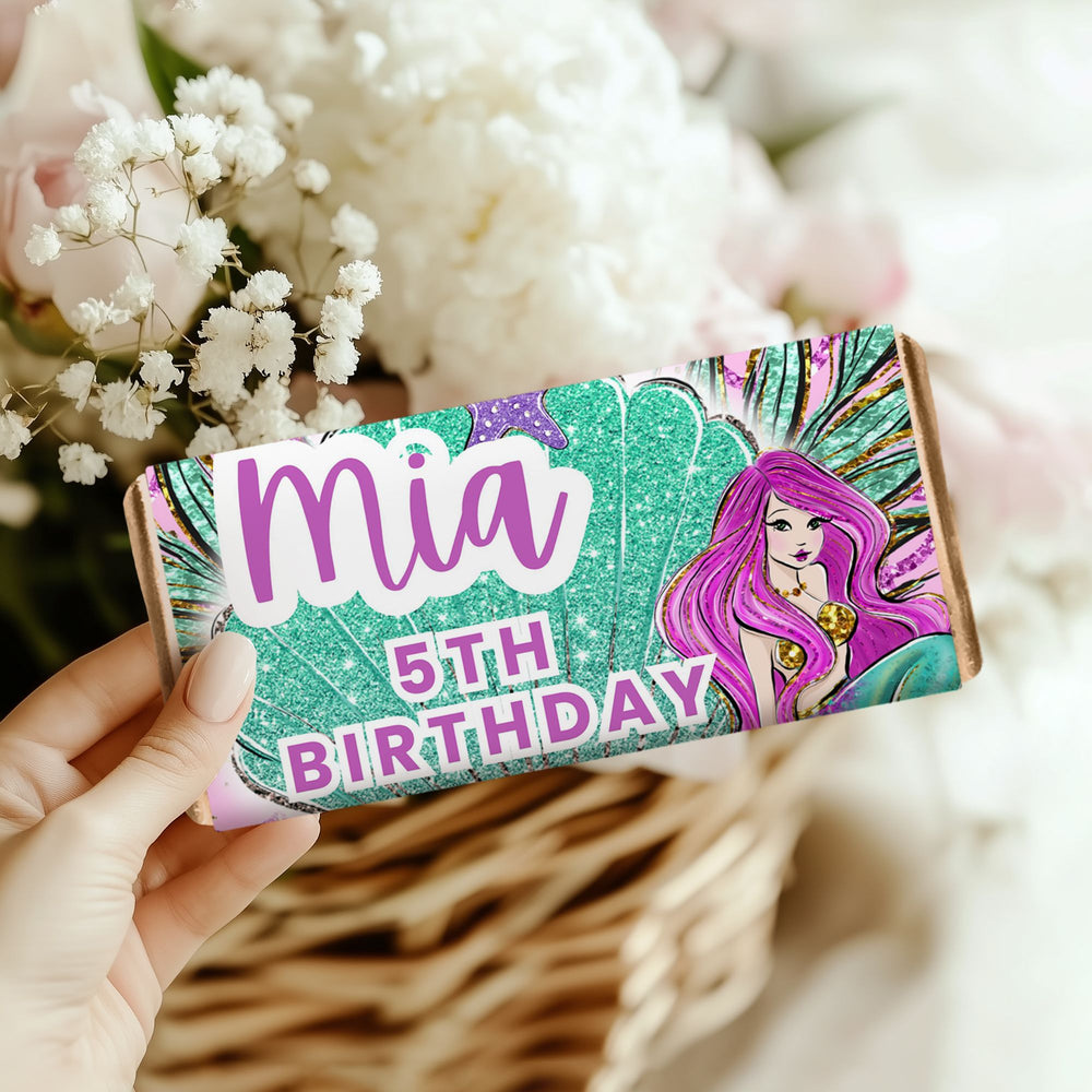 a hand holding a mermaid chocolate bar with some flowers