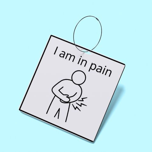 Square sign with a drawing of a person in pain and text 'I am in pain' on a light blue background for the Spiritual, Emotional & Medical Communication Cards