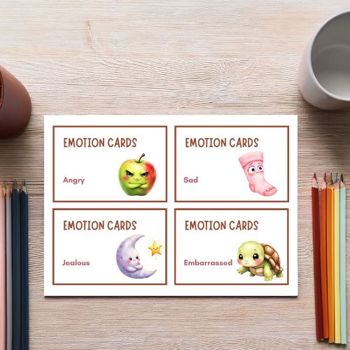 Emotion cards with illustrations on a wooden surface with pencils and a mug.